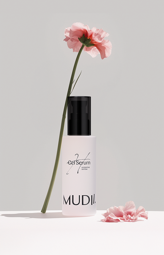 Serum do włosów Mudii z delikatnym kwiatem w minimalistycznej kompozycji.